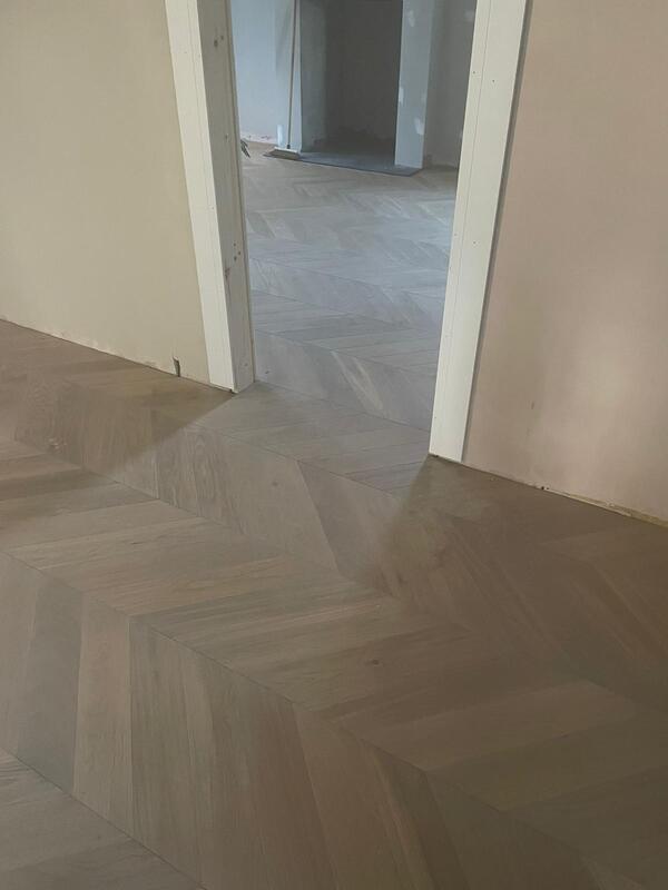 Chevron parquet wood flooring in hallway and living room