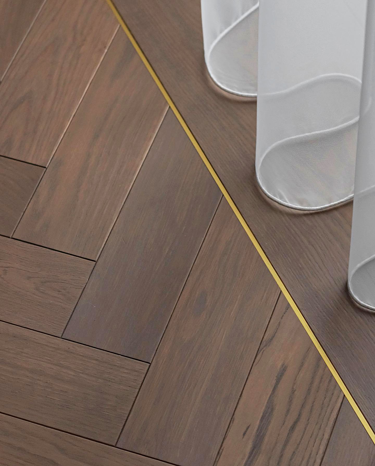 Brushed brass inlay between herringbone parquet and an oak border
