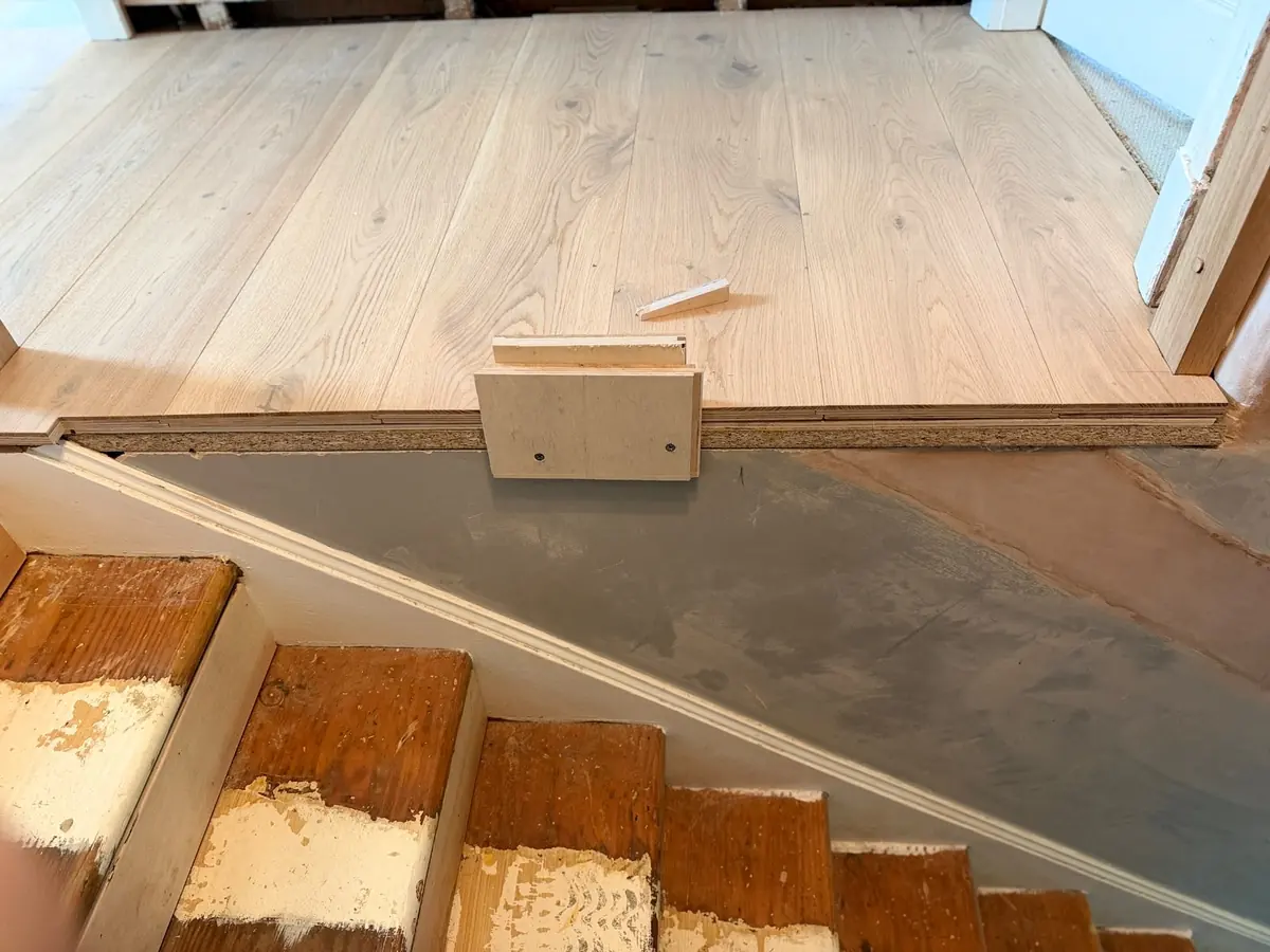 Landing floor edge being finished with a bespoke oak profile above the original staircase before cladding