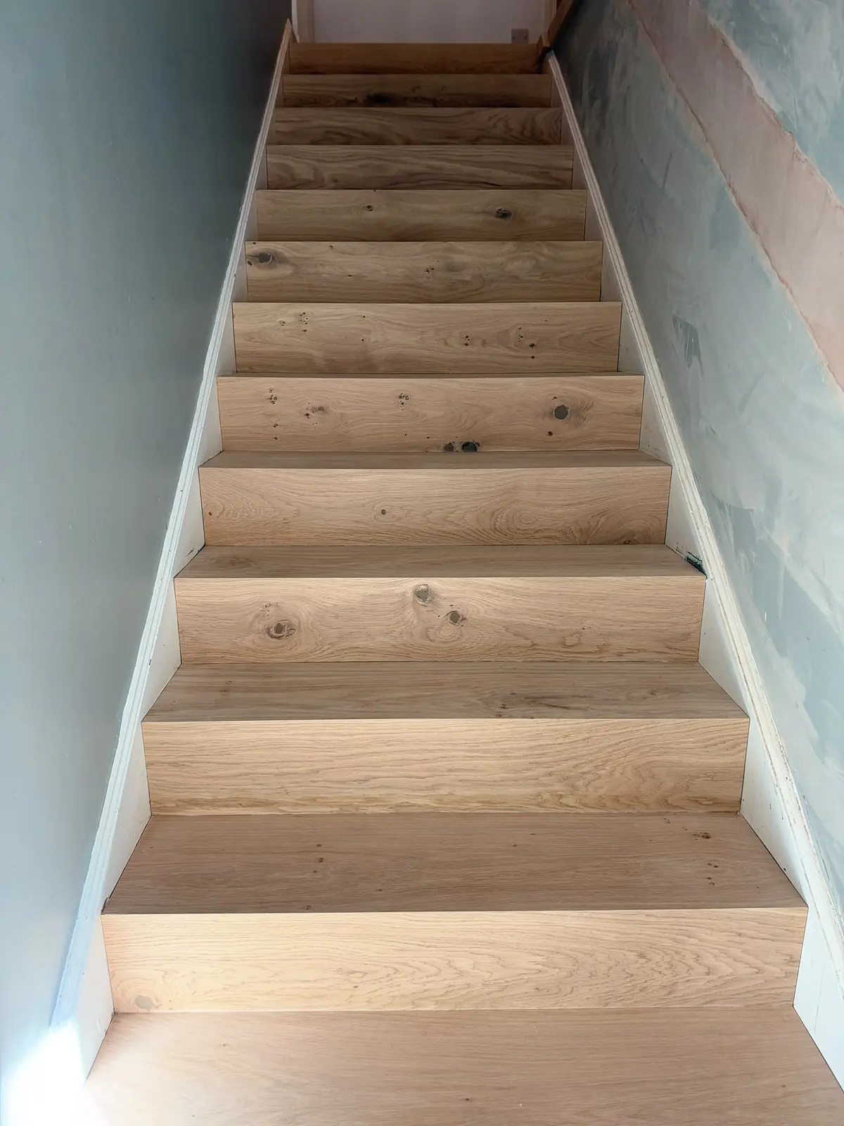 Bespoke oak stair treads and risers matching the wide plank hallway floor