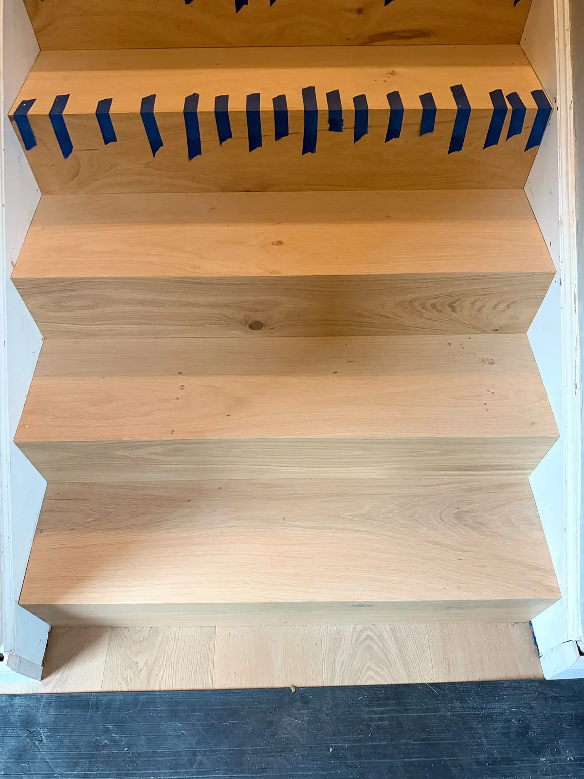 New oak stair treads and risers taped in place while the adhesive sets