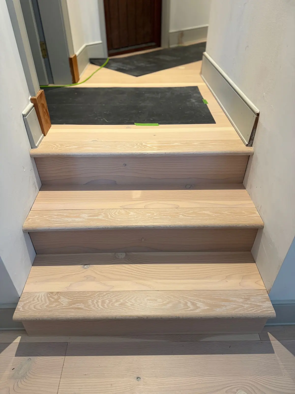 Three steps clad in Douglas fir leading to the front hallway