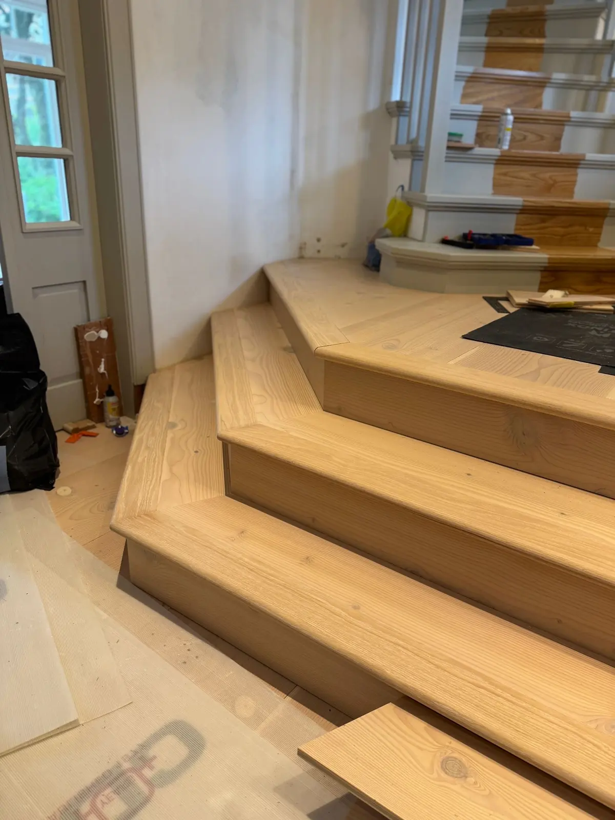 Douglas fir clad steps beside a painted staircase, with mitred nosings