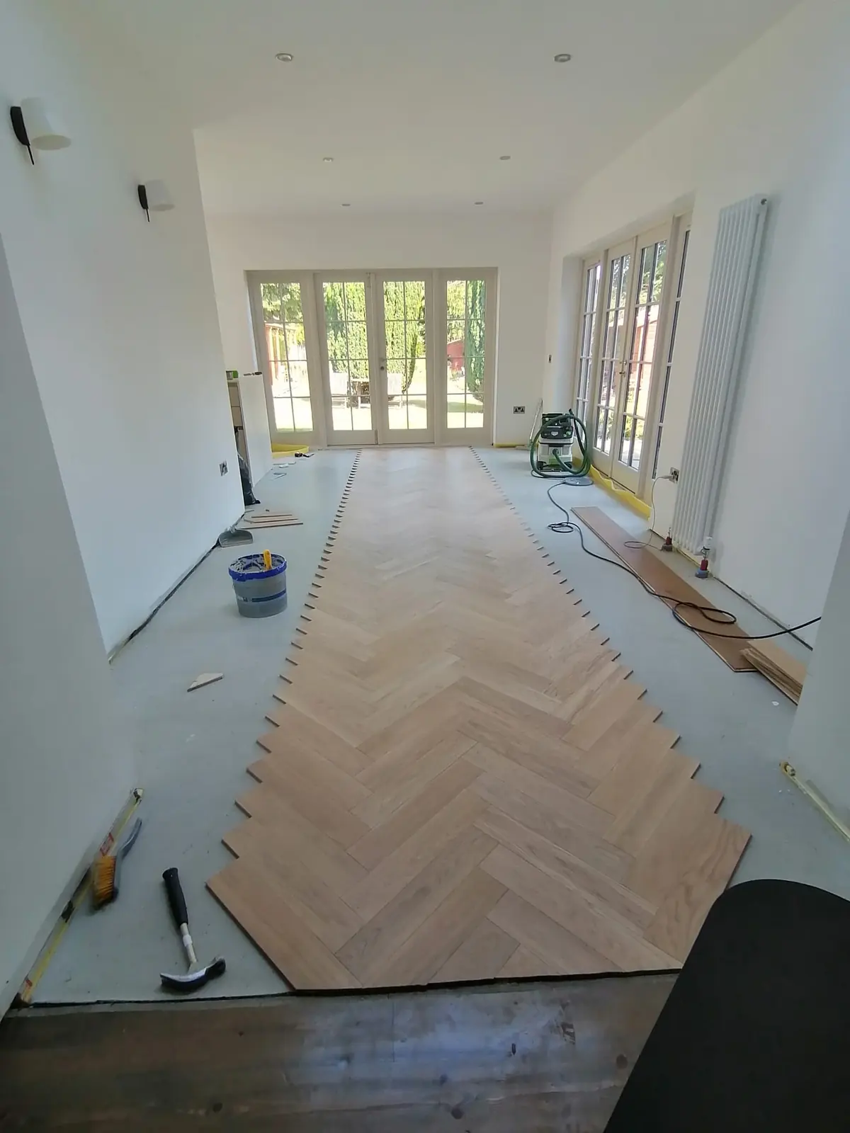 Herringbone parquet laid from a centre line in a bright extension with a roof light