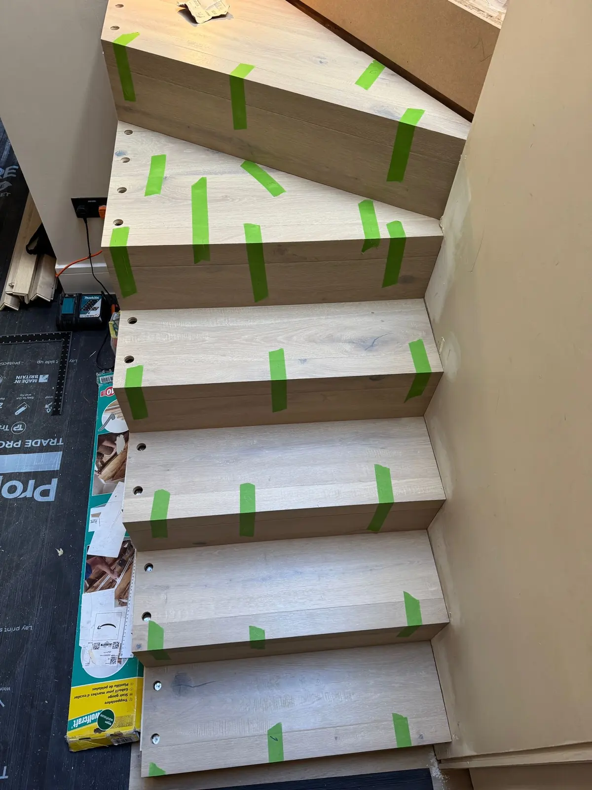 Bespoke oak stair treads drilled for metal spindles and taped while the adhesive cures