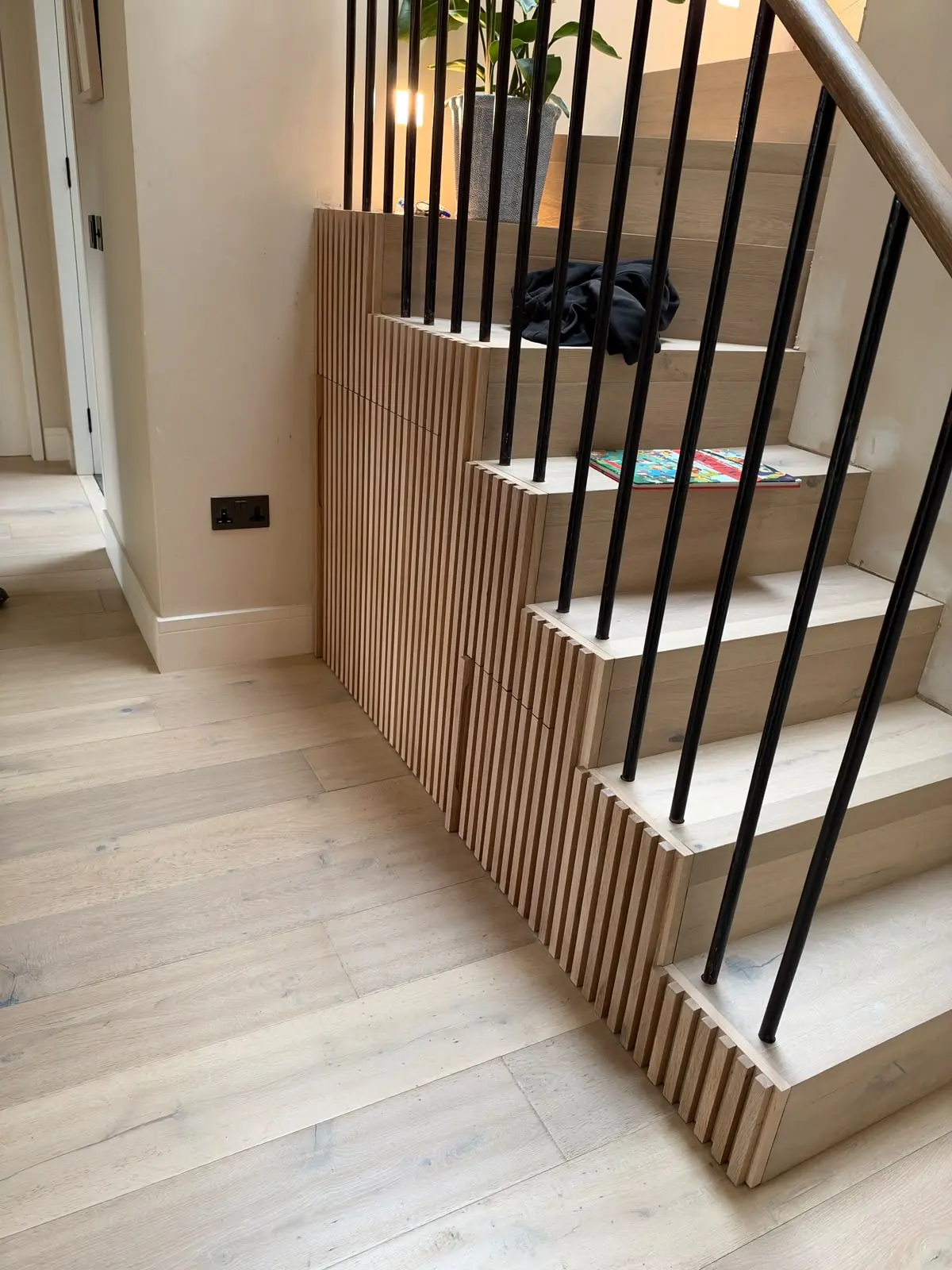 Oak-clad staircase with slatted solid oak joinery and black metal spindles