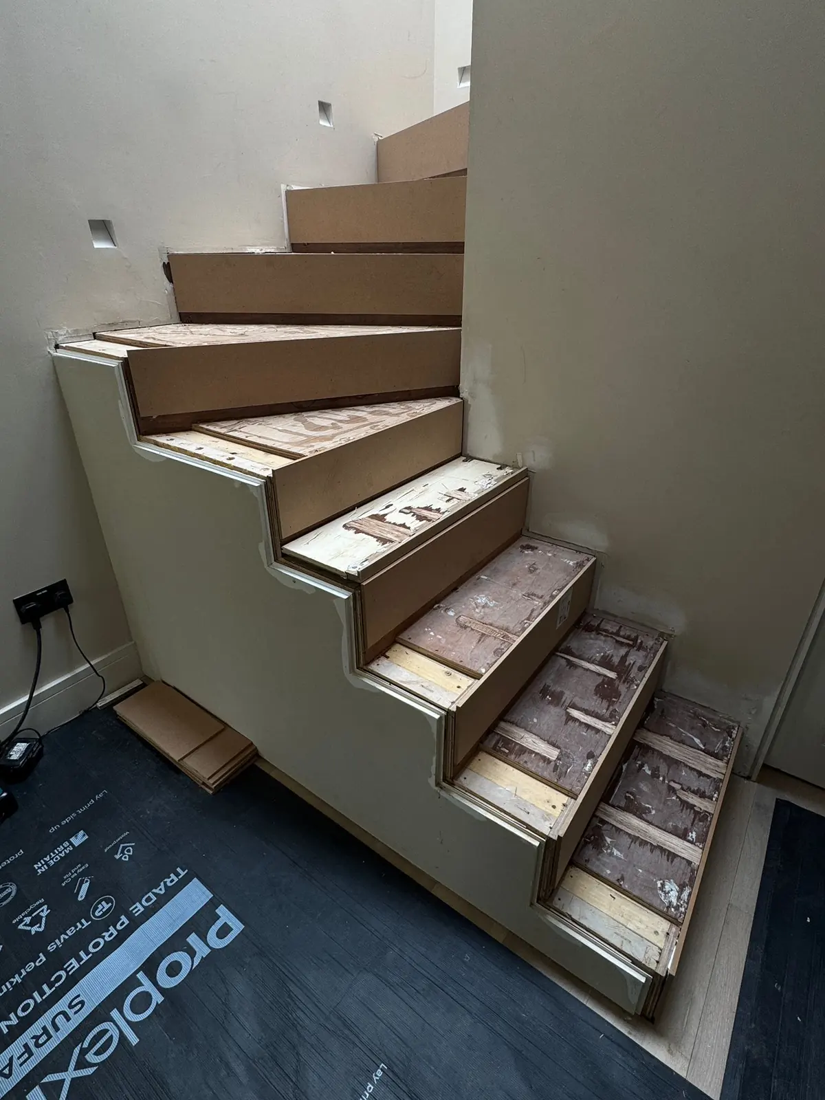 Staircase with the old cladding removed, showing the steel and plywood structure before new oak treads