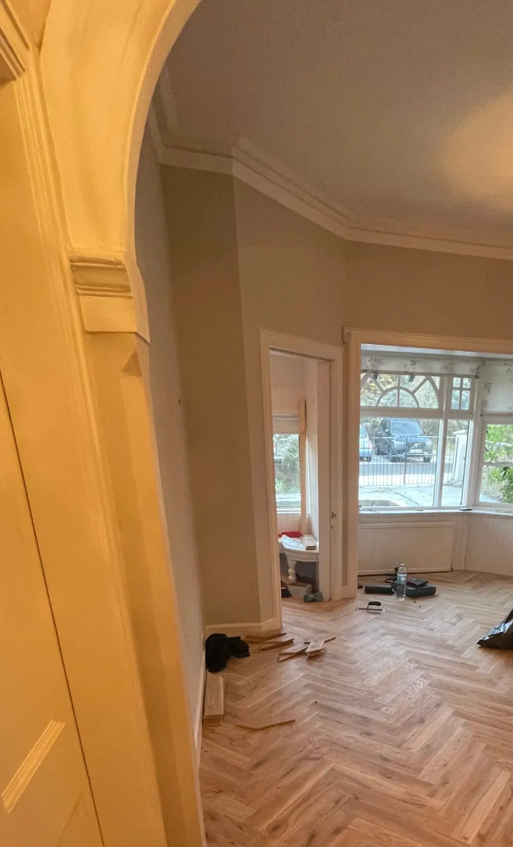 Herringbone parquet seen through the hallway arch towards the bay window