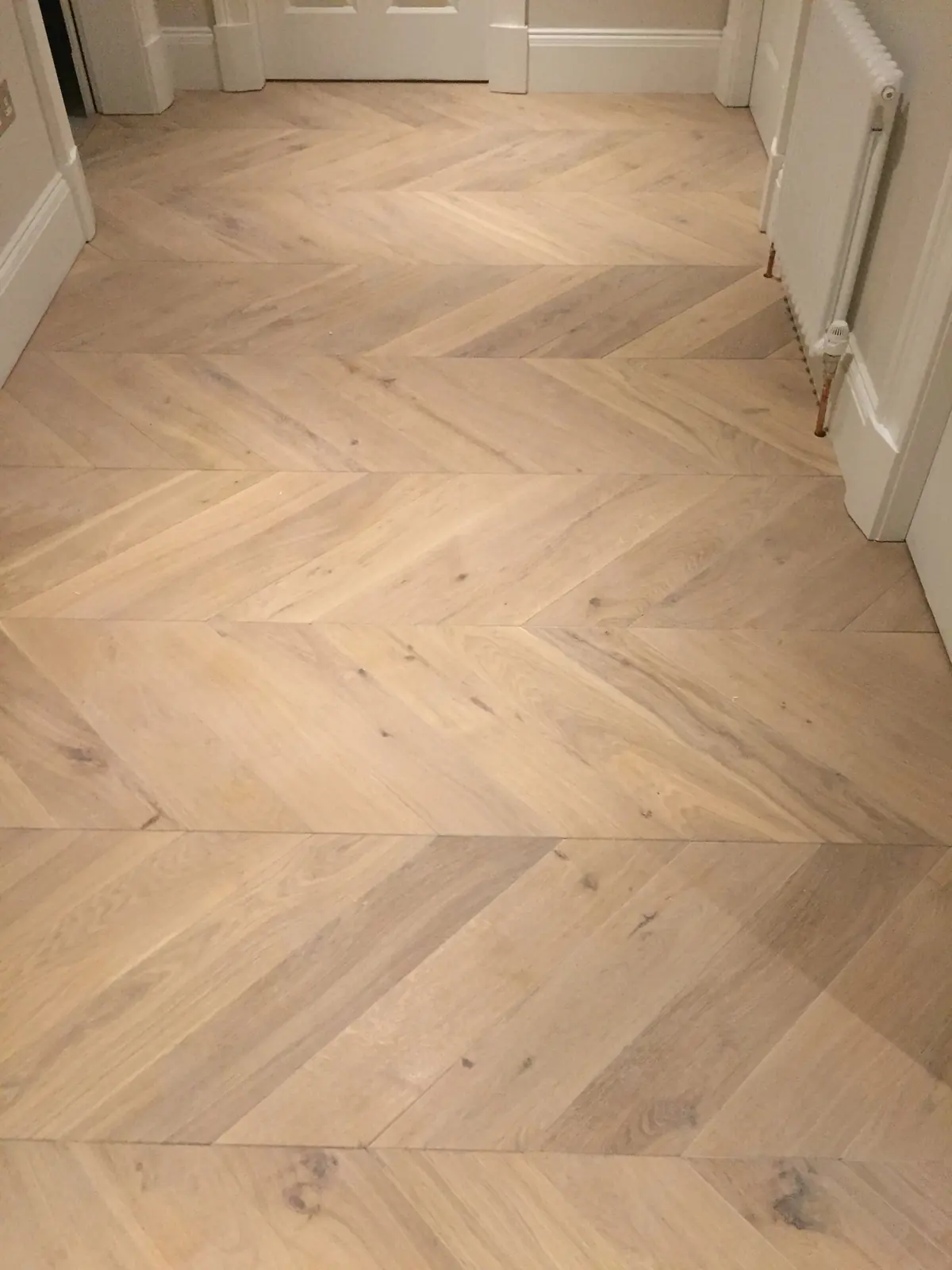 Chevron parquet hallway with a border, leading down oak-clad steps