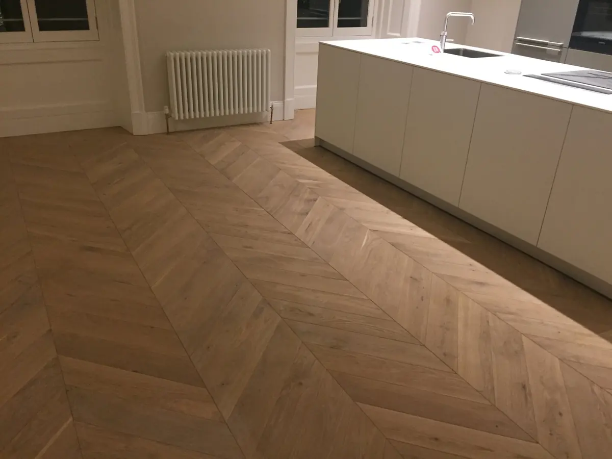 Chevron parquet running past a white kitchen island