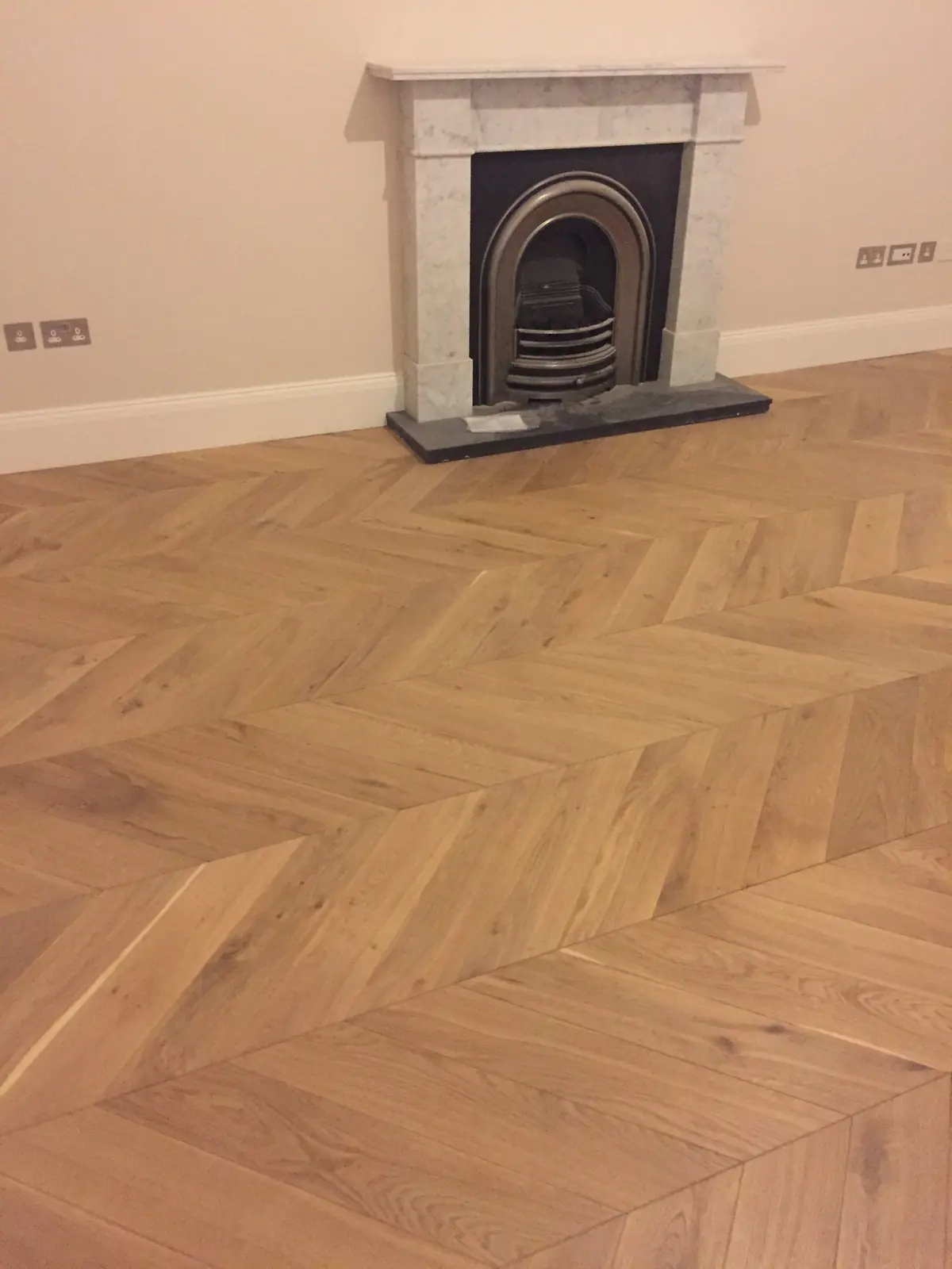 Light Oak chevron parquet beside a period fireplace and sash window