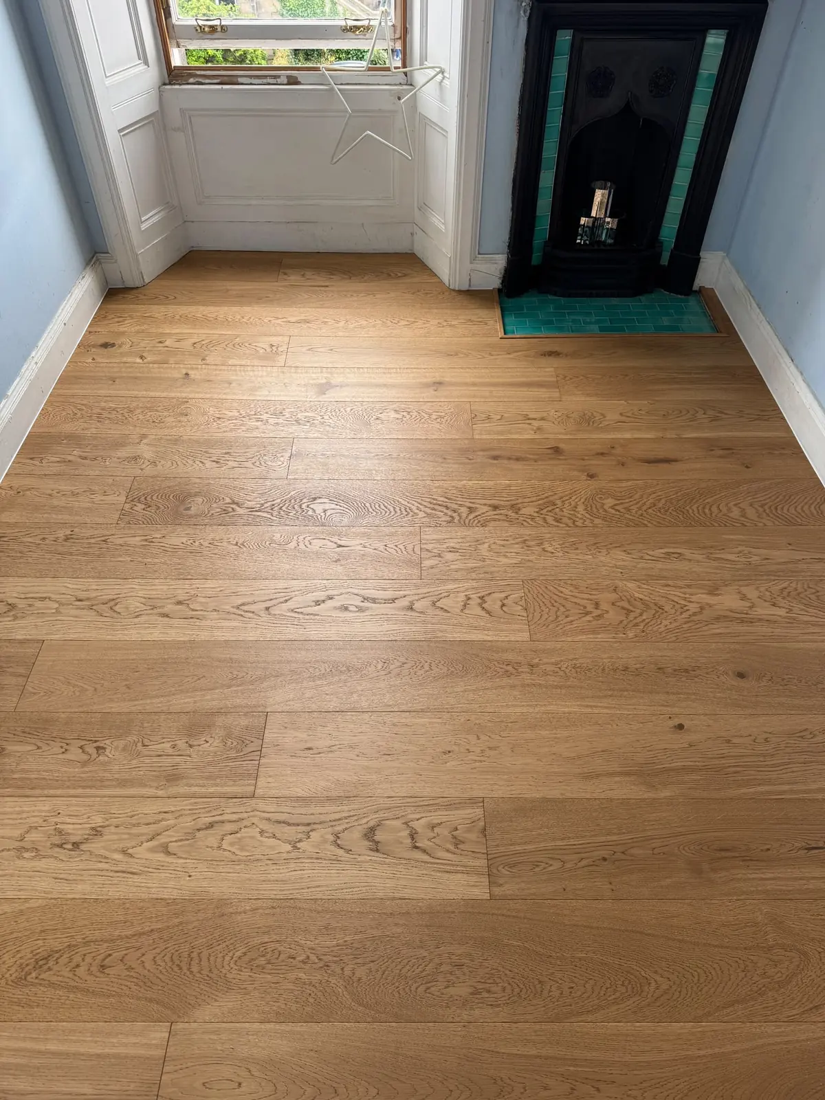 Engineered oak flooring in a small bedroom with a cast iron fireplace