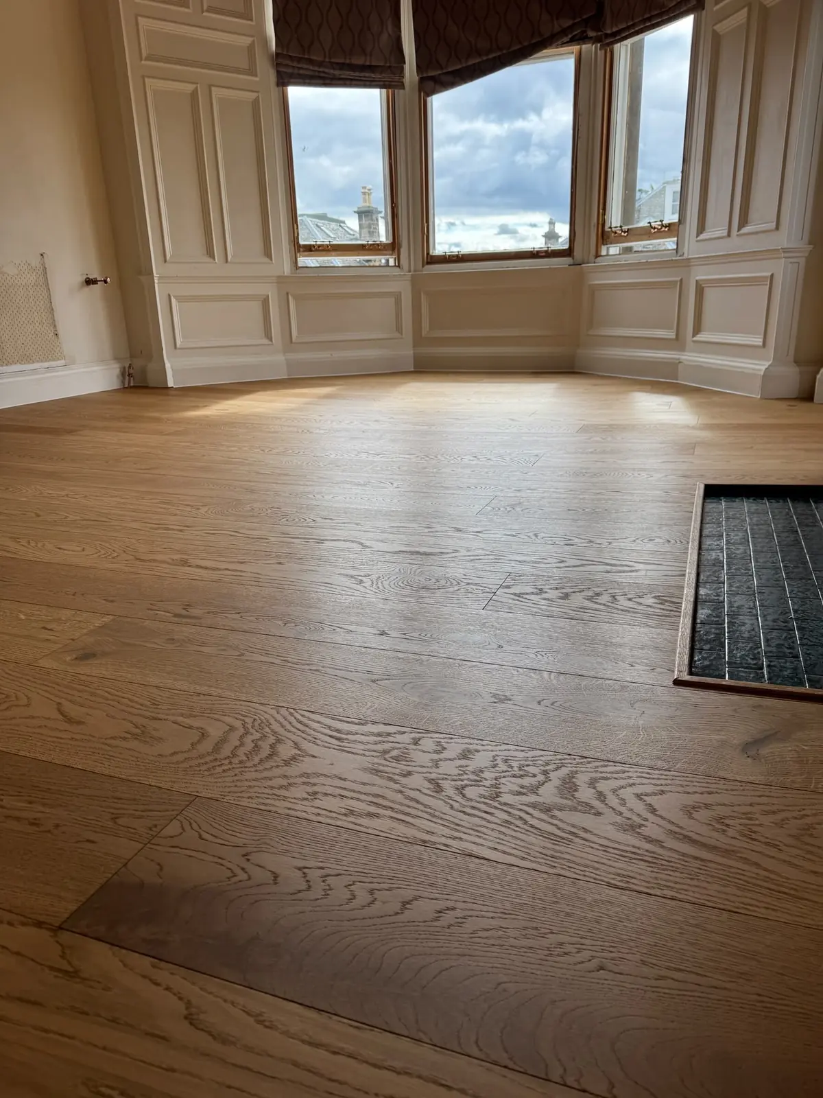 Medium Oak engineered oak flooring in a bedroom with a panelled bay window in an Edinburgh flat