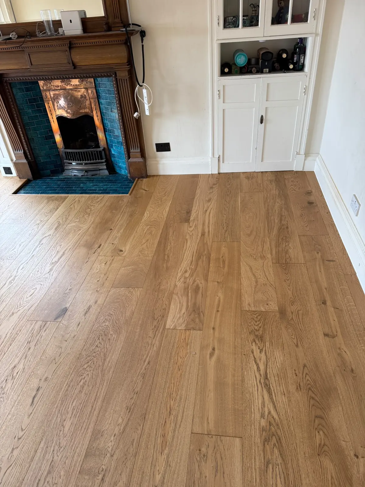 Medium Oak wood flooring beside a Victorian fireplace with blue tiles
