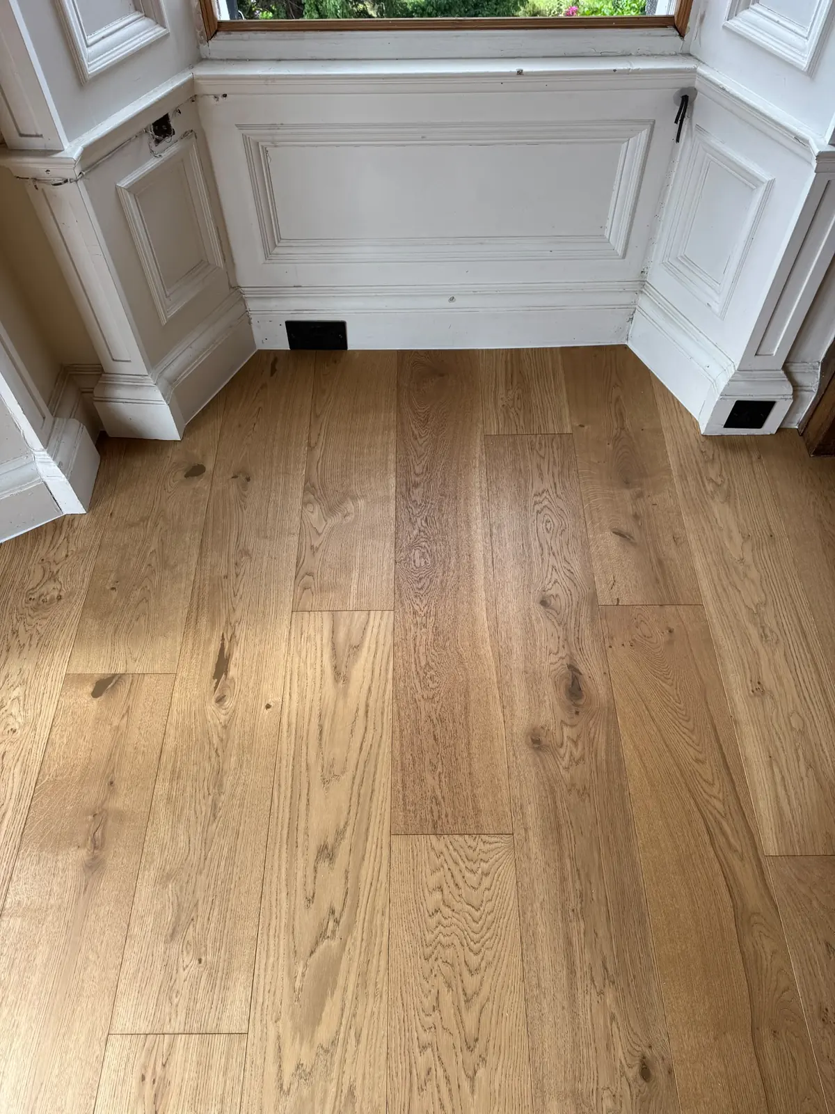 Oak planks fitted neatly into a panelled bay window recess