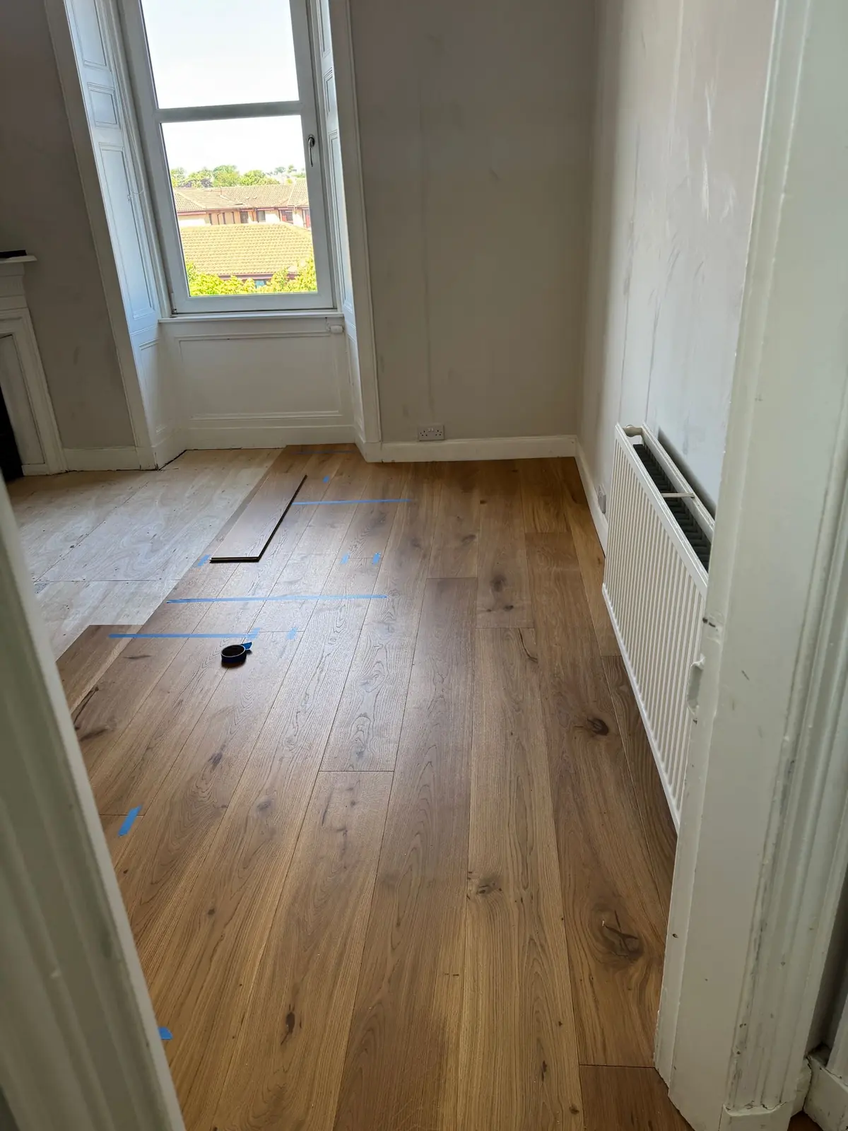 Oak planks being laid over new plywood in a bedroom