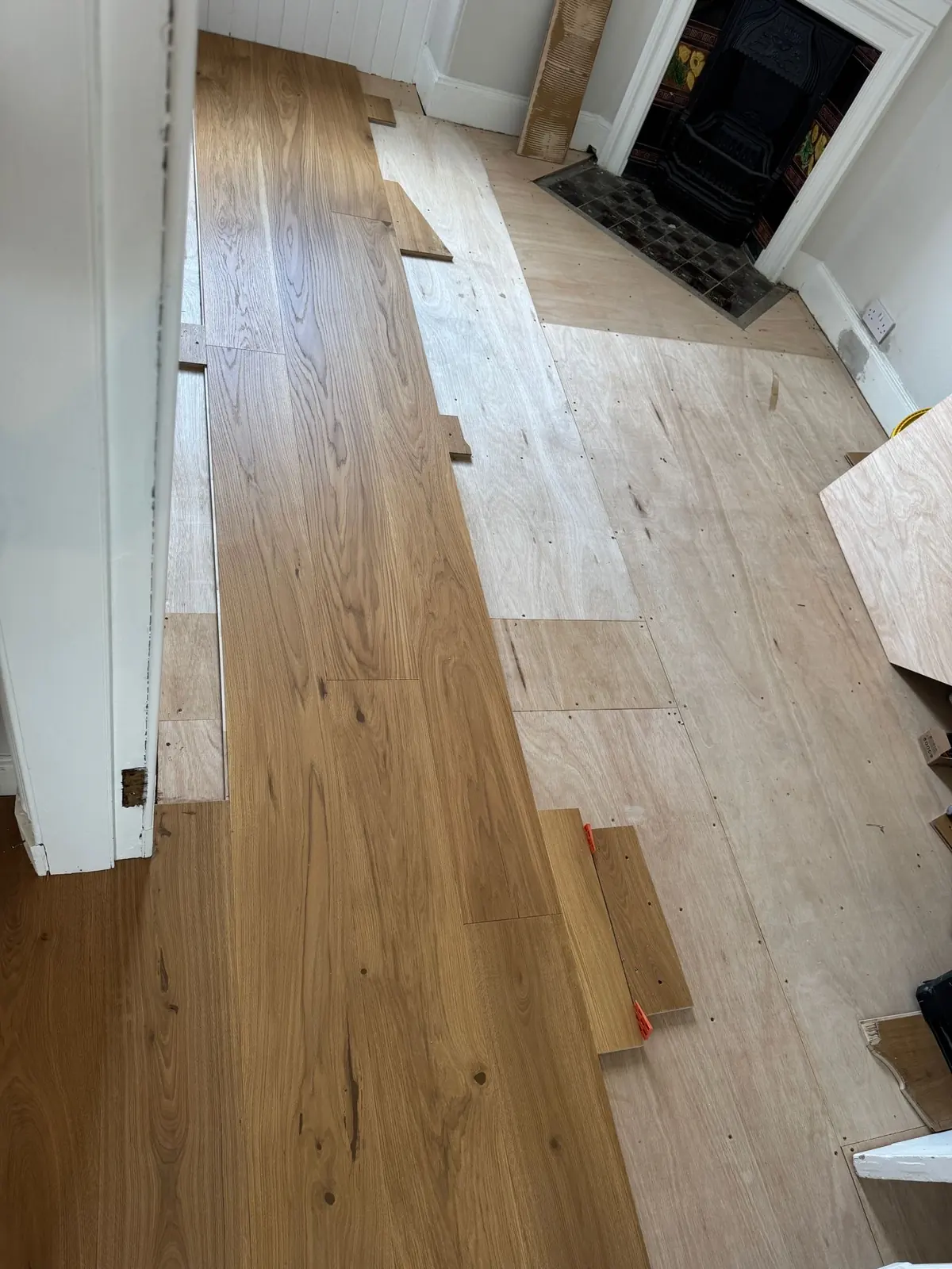 Plywood subfloor with oak planks being laid in a bedroom