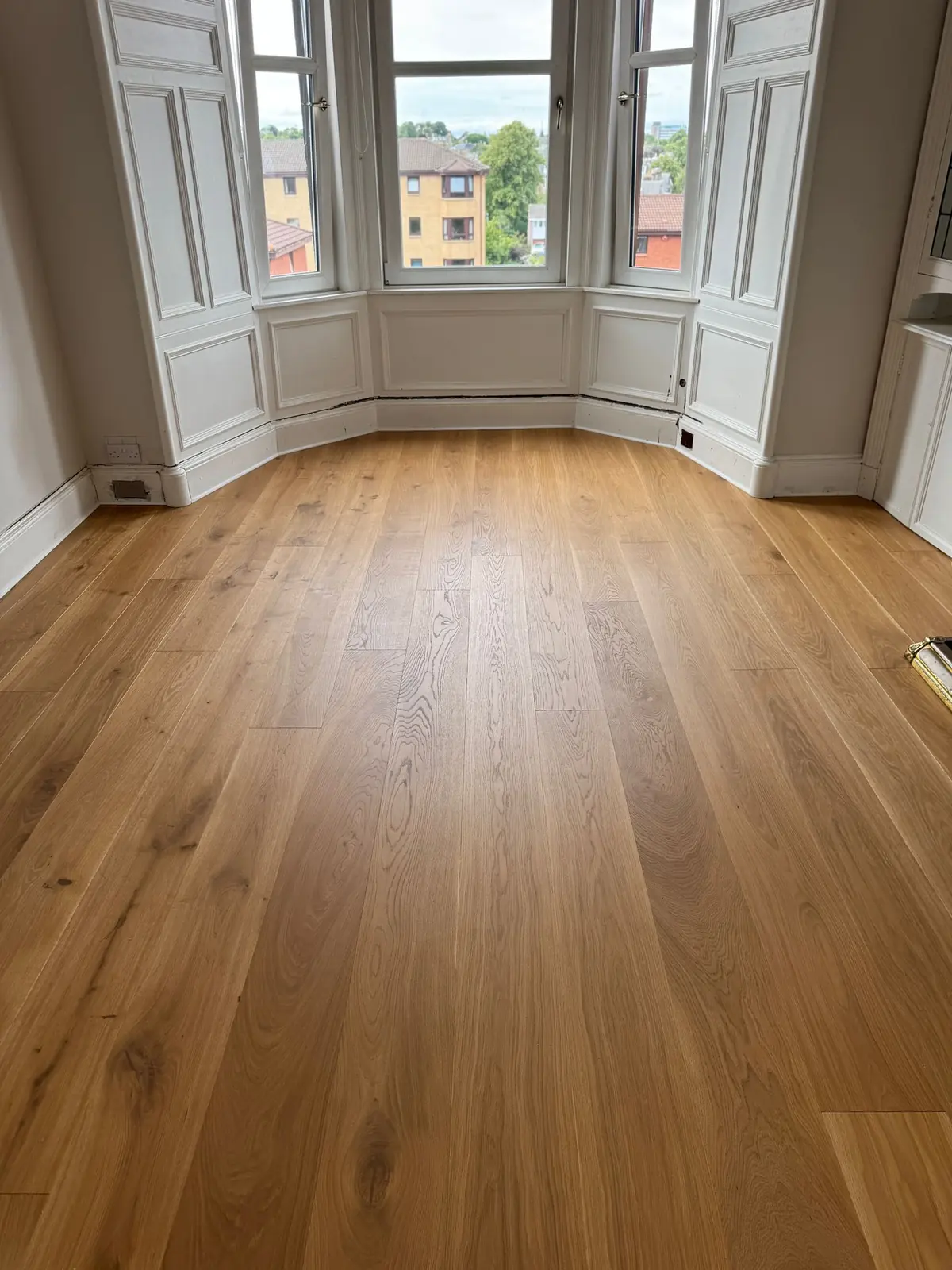 Warm oiled oak floor with a bay window and period panelling