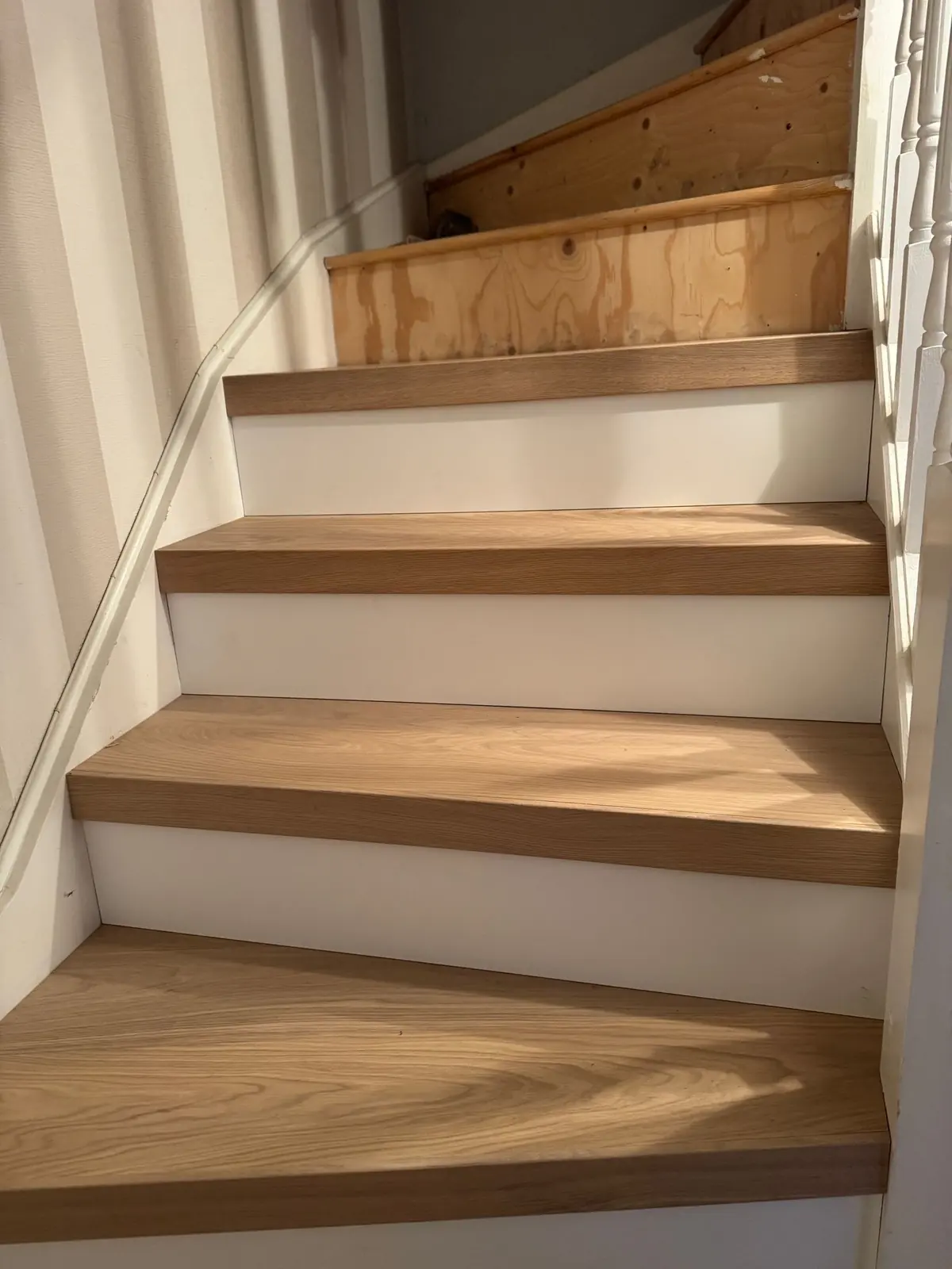 Lower oak treads and white risers fitted while the upper steps are still being clad