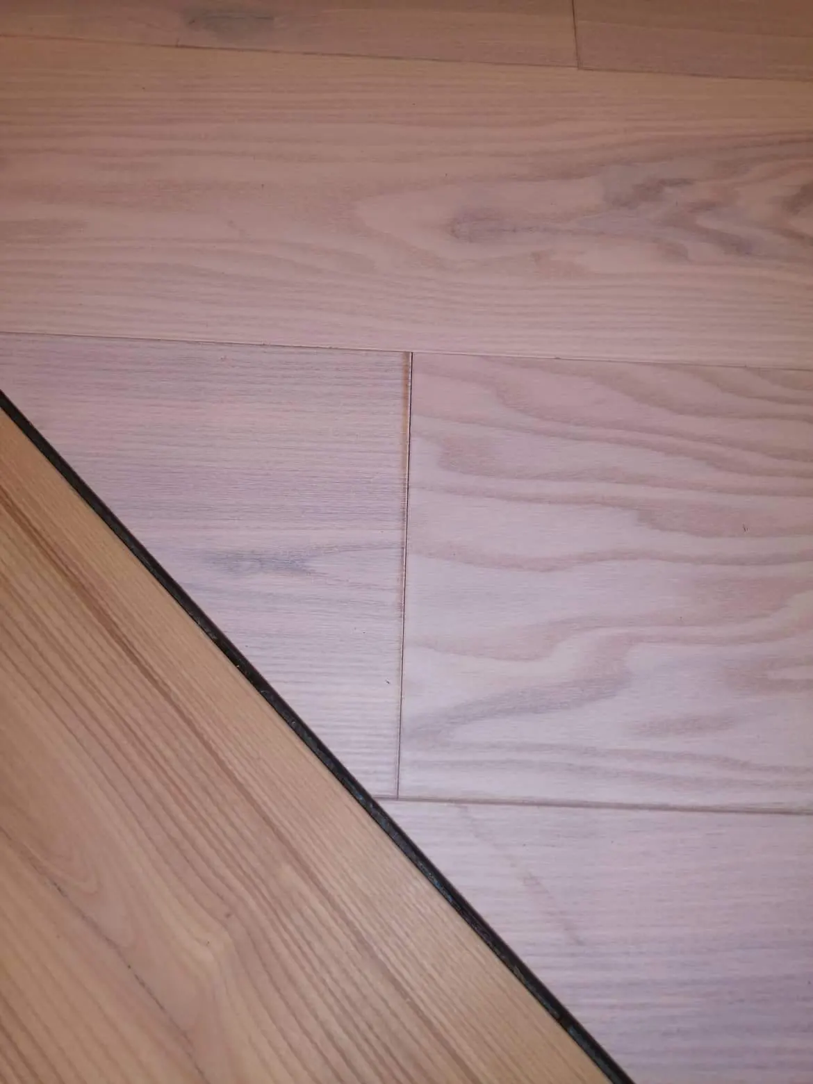 Detail of White Ash and Ash Natural engineered planks meeting at a joint between two office areas