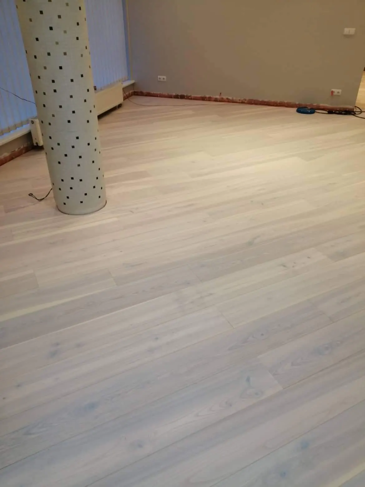 White oiled engineered ash flooring fitted around a column in an open-plan office in Vilnius