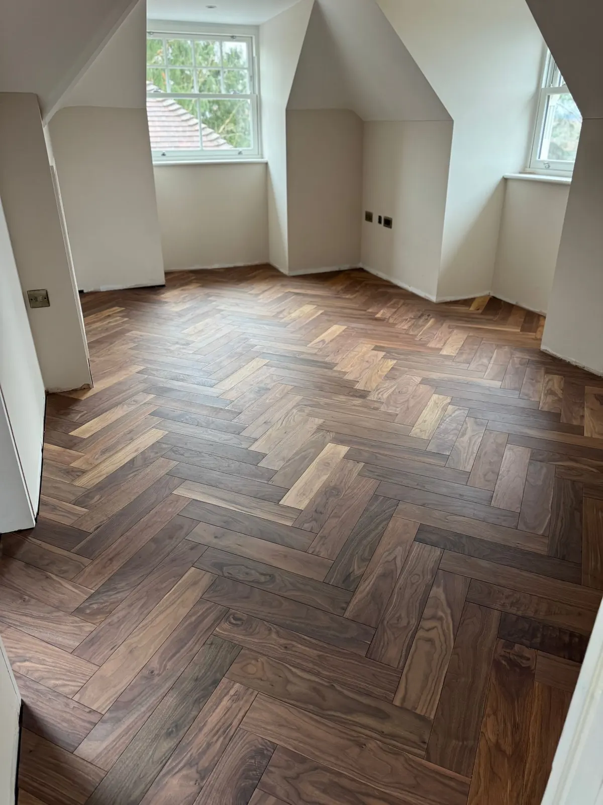 Walnut herringbone parquet in a top-floor bedroom with dormer windows