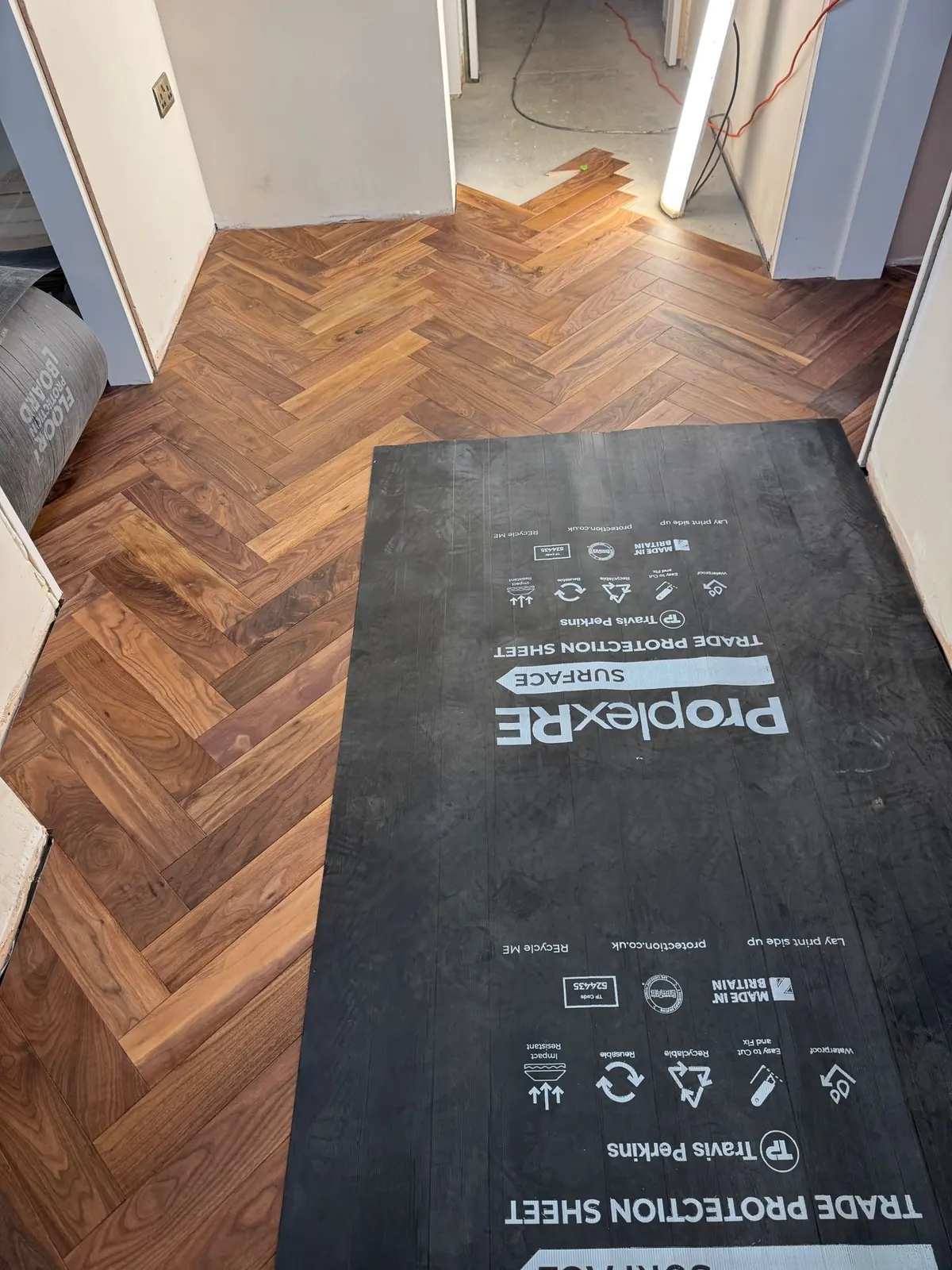 Finished walnut herringbone parquet protected with floor protection sheets