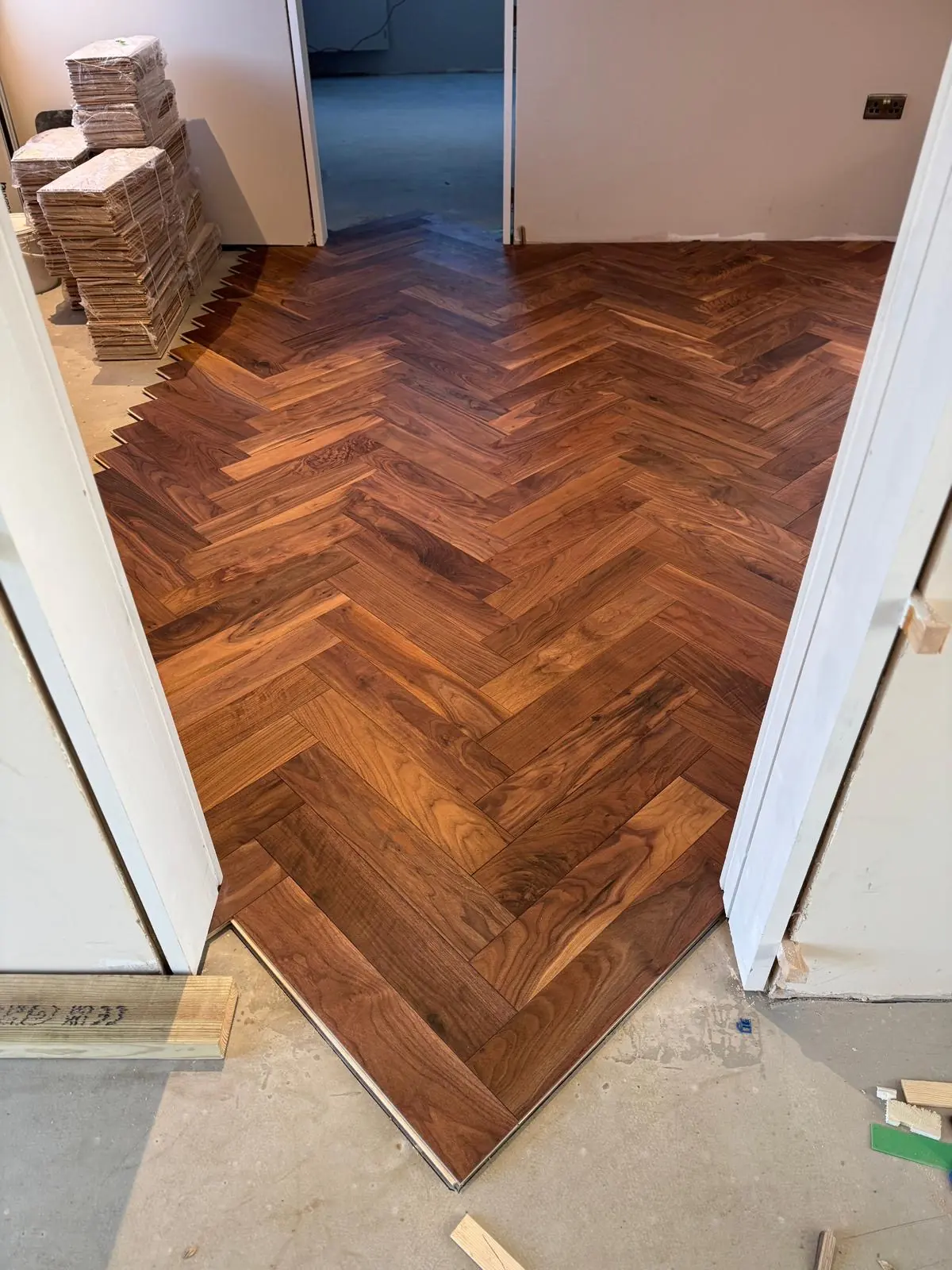 First rows of walnut herringbone parquet glued down over underfloor heating