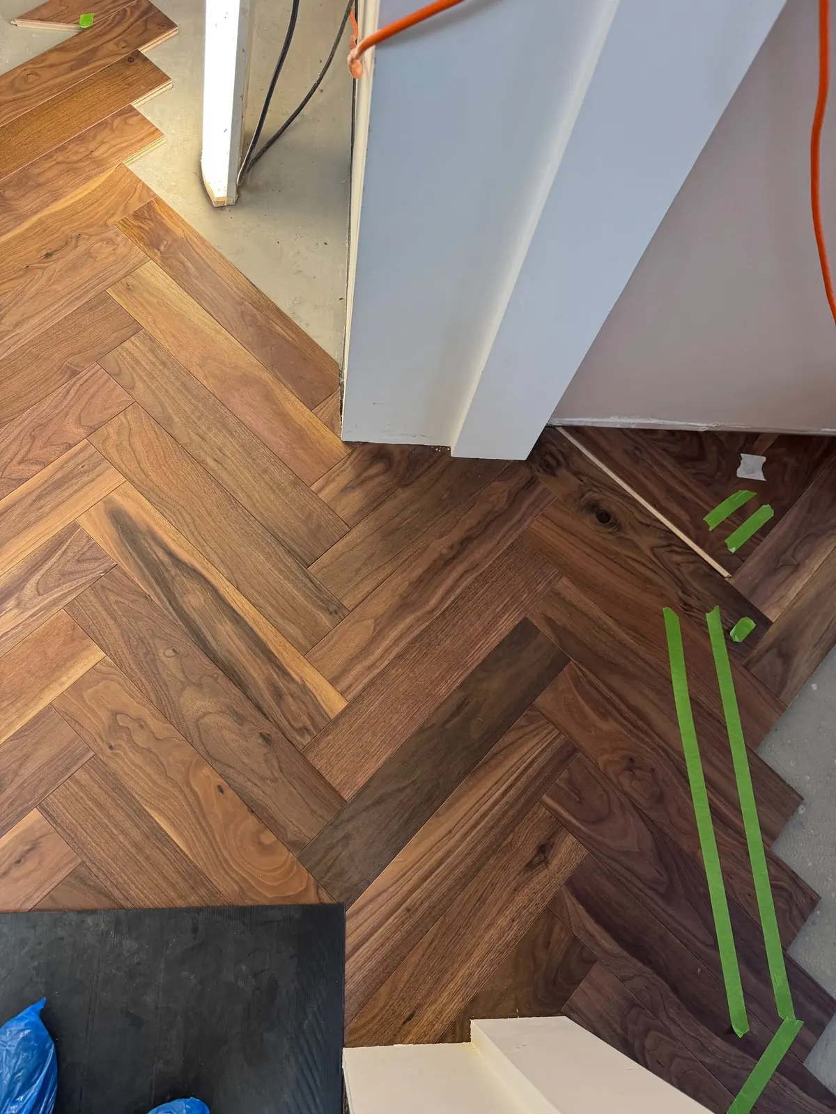 Flush transition between walnut herringbone parquet and porcelain bathroom tiles