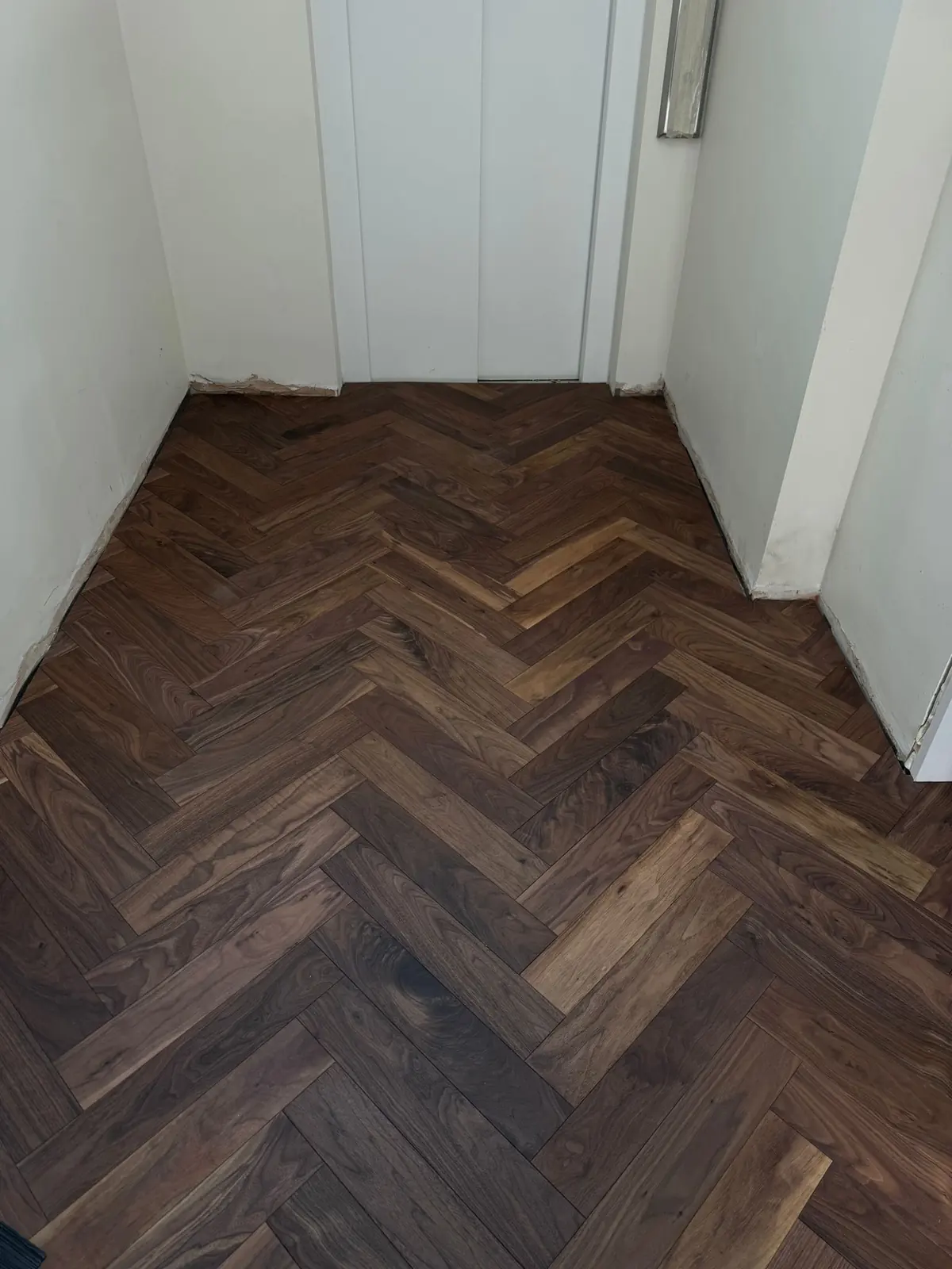 Walnut herringbone pattern carried through a door frame on the centre line