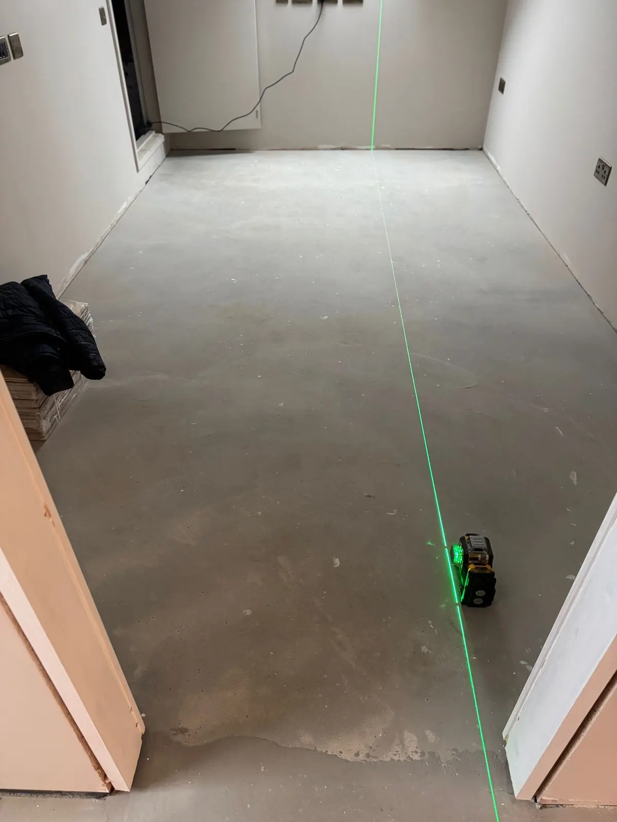Laser line set out on a cleaned and primed screed before walnut herringbone parquet installation