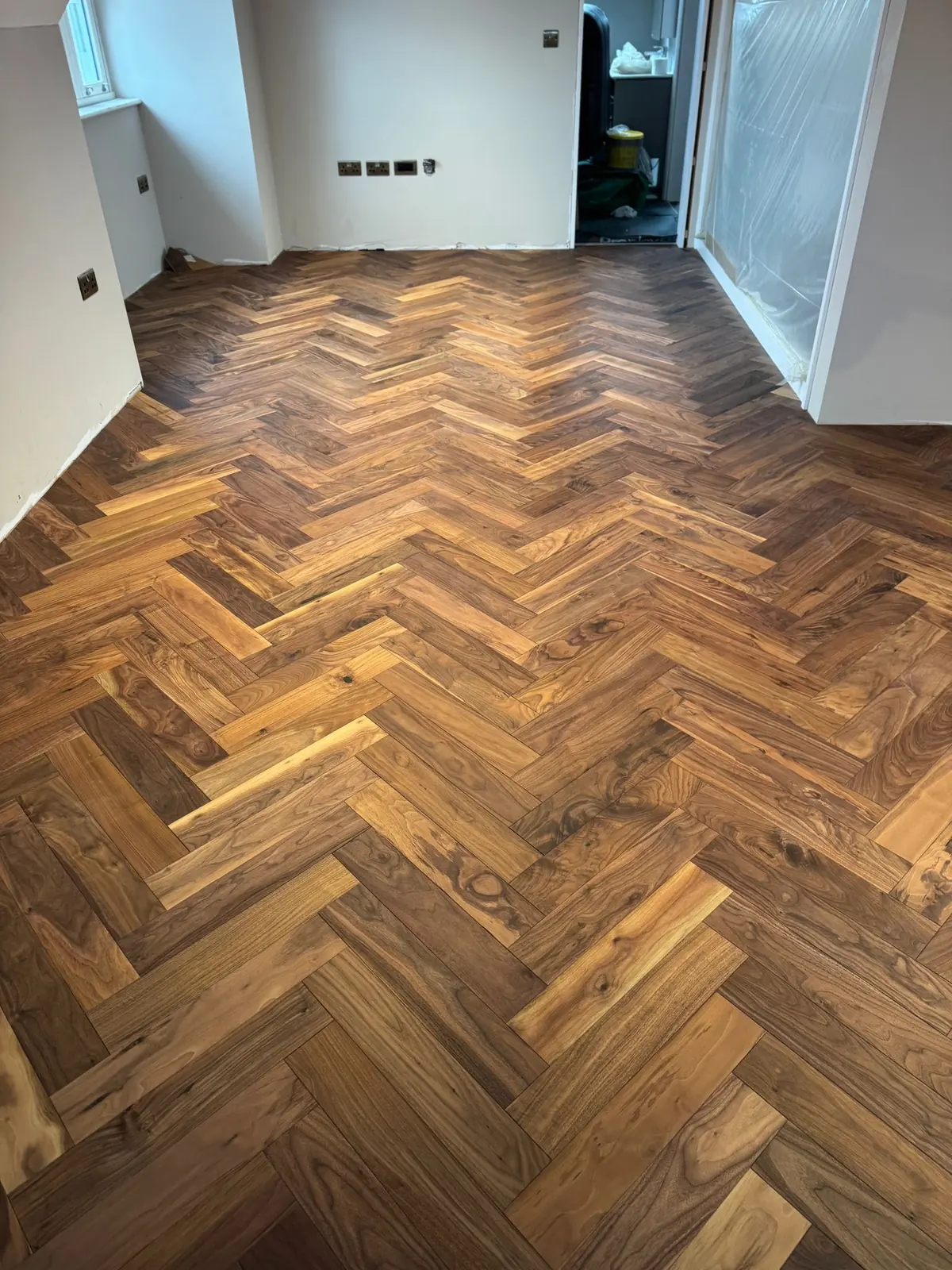 Walnut herringbone parquet being installed room by room with packs of blocks ready