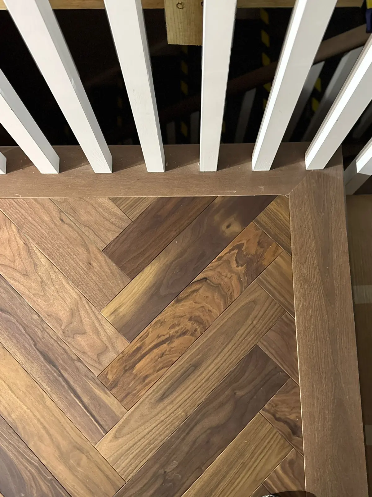 Walnut herringbone parquet finished with a straight border along the banisters