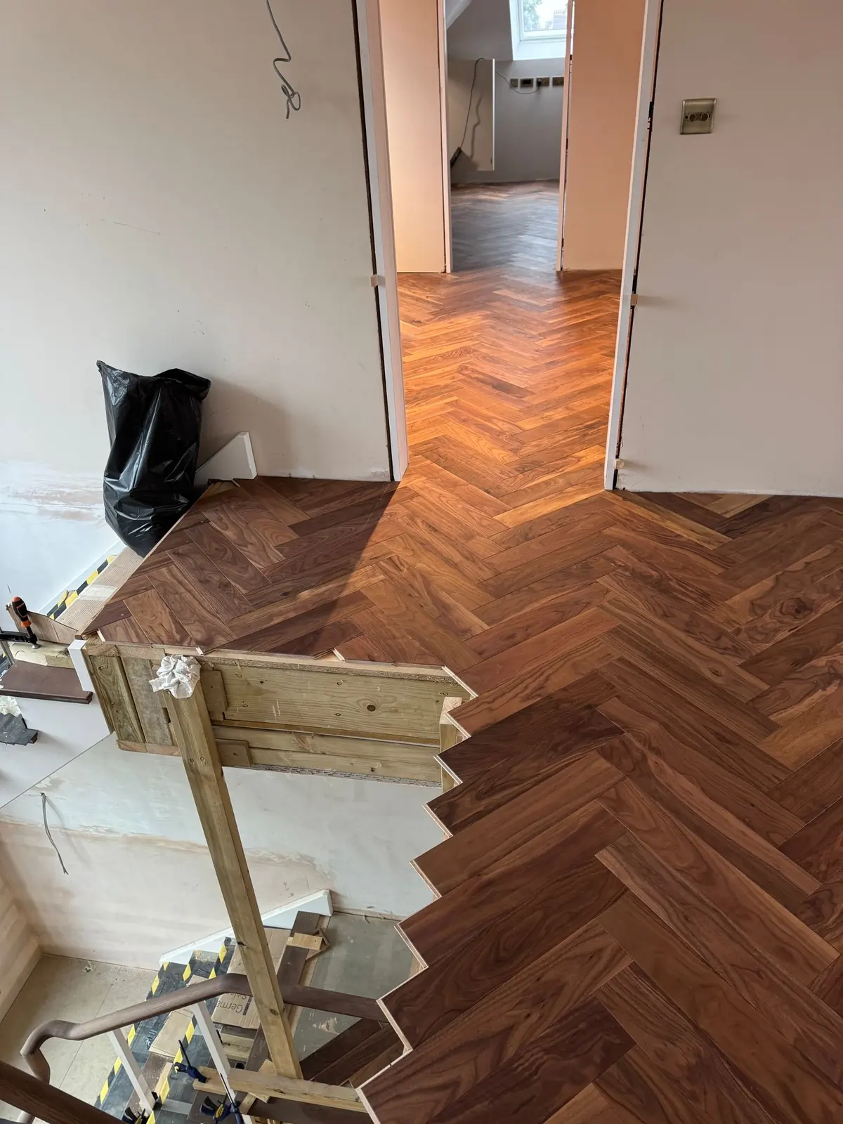 Walnut herringbone parquet across a landing and hallway in a central London home
