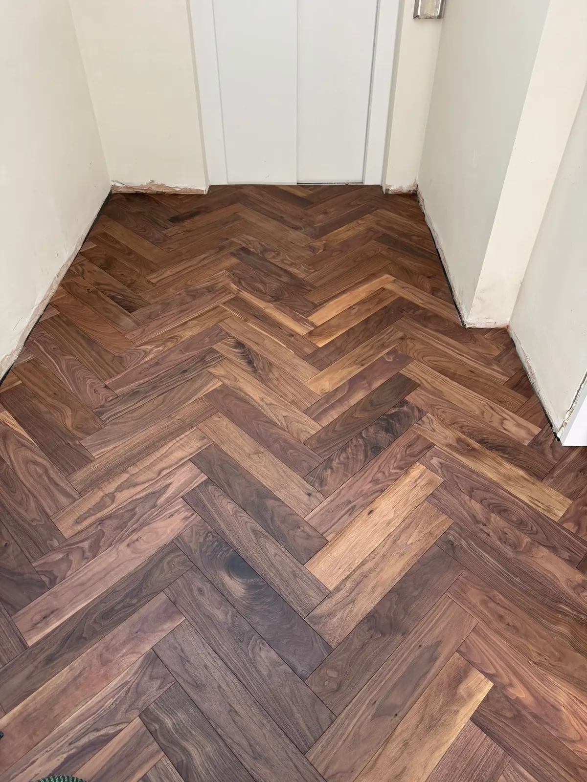 Walnut herringbone parquet in a lift lobby on an upper floor