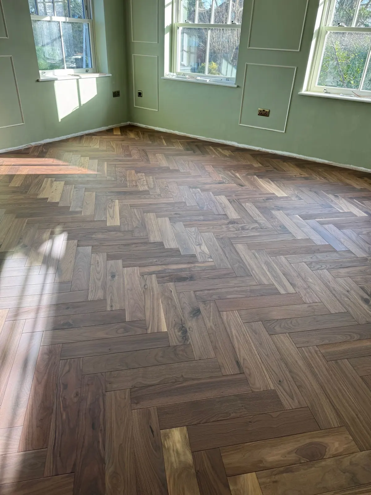 Walnut herringbone parquet seen through a doorway in warm evening light